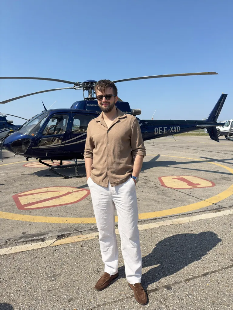 Michael Rebel standing beside a helicopter on a landing pad.
